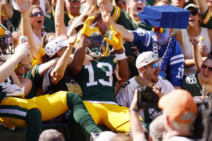 Green Bay Packers wide receiver Dontayvion Wicks (13) does the Lambeau leap into the crowd after scoring a touchdown during an NFL game between the Indianapolis Colts and the Green Bay Packers on September 15, 2024 at Lambeau Field in Green Bay, WI.